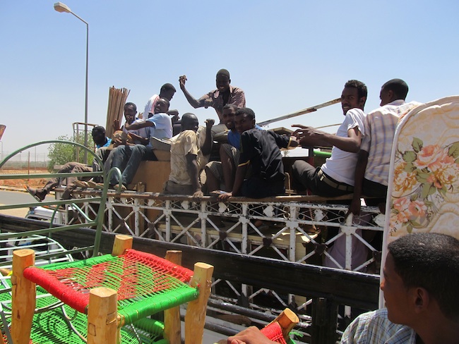 Moving day in Khartoum, a bunch of sudanese precariously riding atop a truck