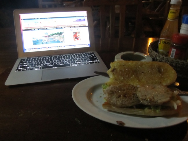 eating pork sandwich while travel blogging 