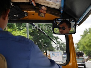 tuk tuk driver in bangkok through mirror