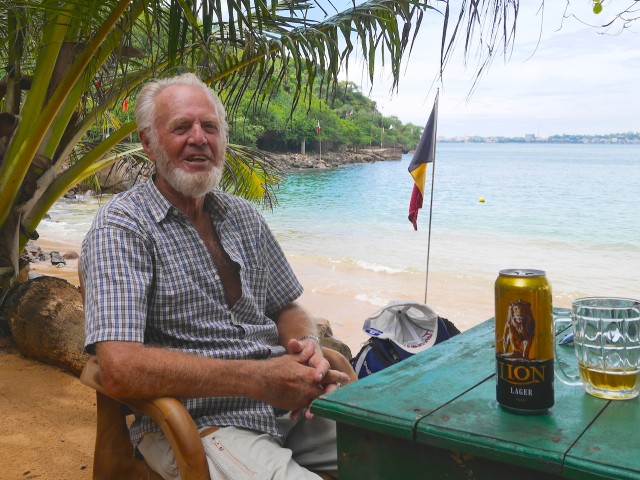 an old norwegian sea captain drinking a beer on a beach