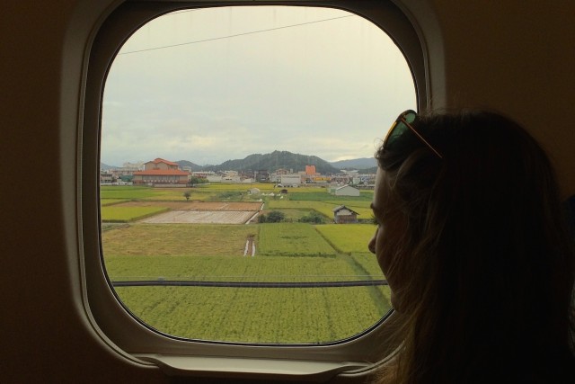 looking at the japanese country side through the window of the bullet train